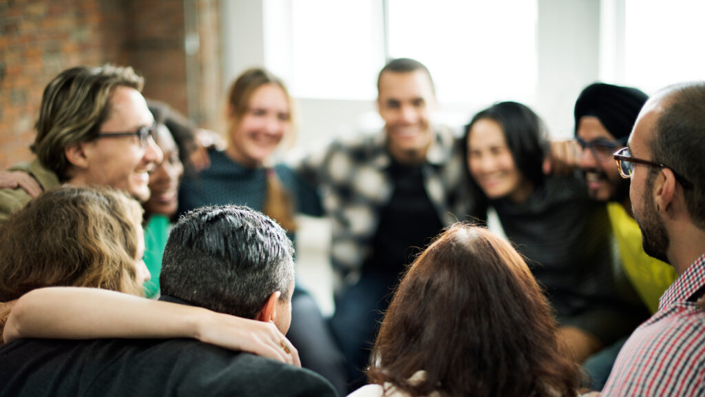 Happy people huddling in a group in the center of a room
