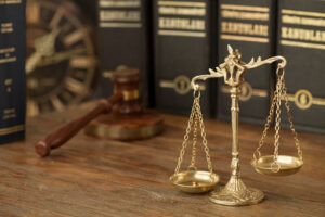 scales and gavel on a table with law textbooks in the foreground.