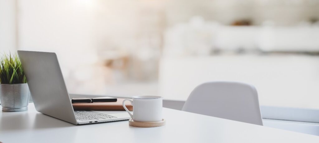 Computer and mug on an empty desk of a professional or intern
