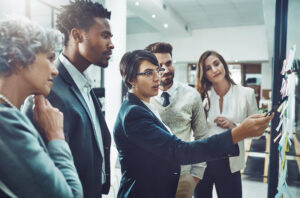 Group of business professionals and board members pointing at a board and discussing