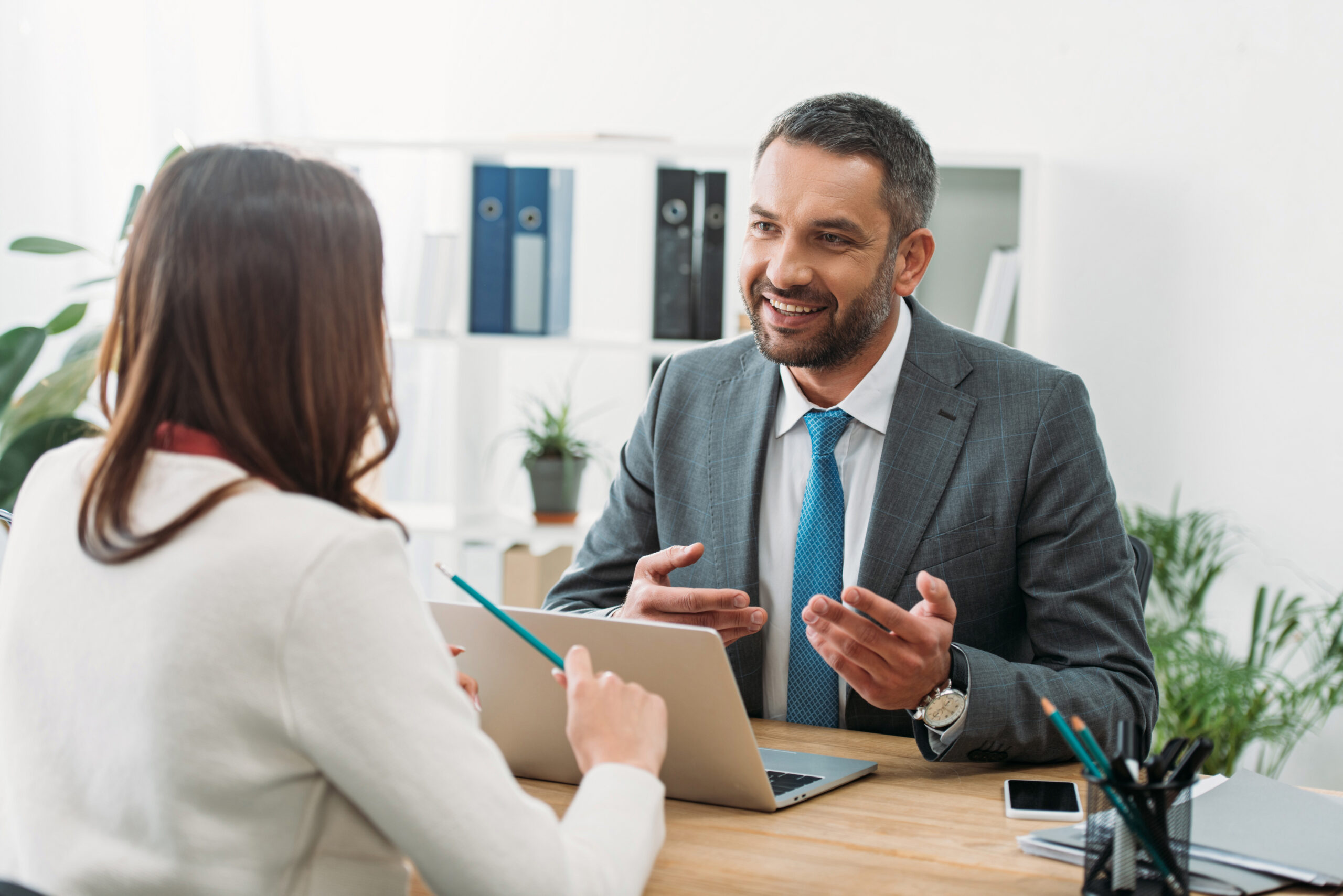 consultant sitting at table with laptop and woman in office giving advise